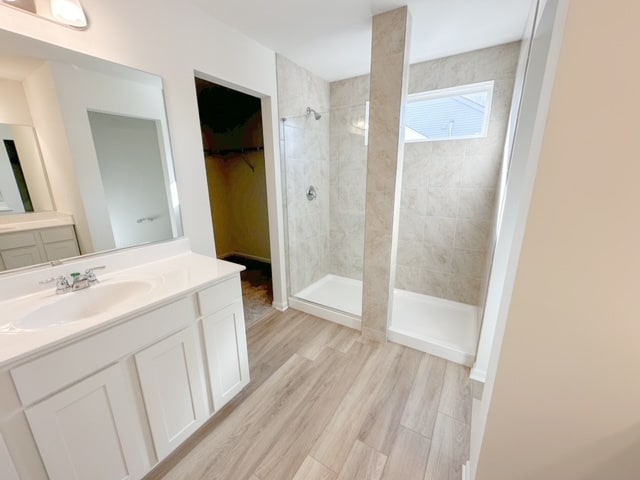 bathroom with tiled shower, wood-type flooring, and vanity