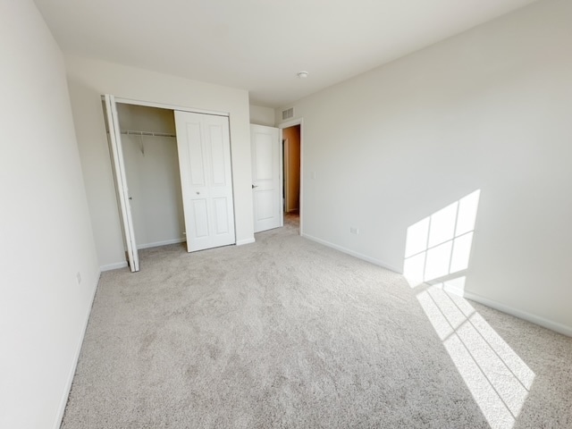 unfurnished bedroom featuring light carpet and a closet