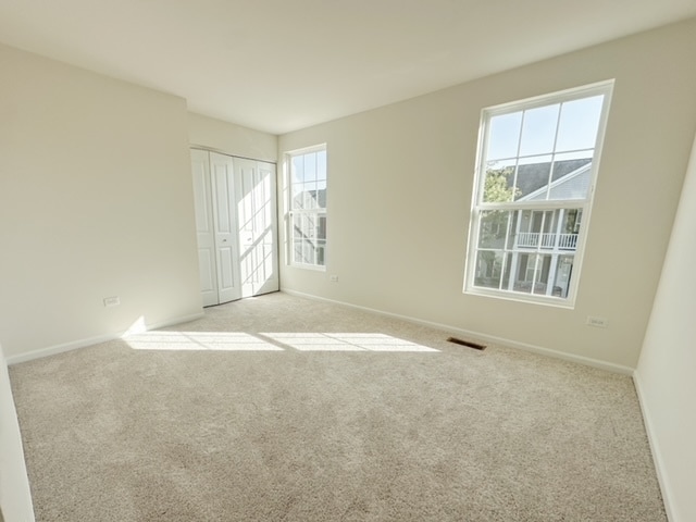 unfurnished room featuring a healthy amount of sunlight and light colored carpet