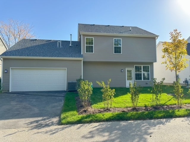 exterior space with central AC, a front yard, and a garage