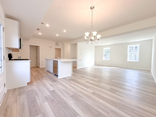 kitchen with a center island, white cabinets, appliances with stainless steel finishes, decorative light fixtures, and light hardwood / wood-style floors