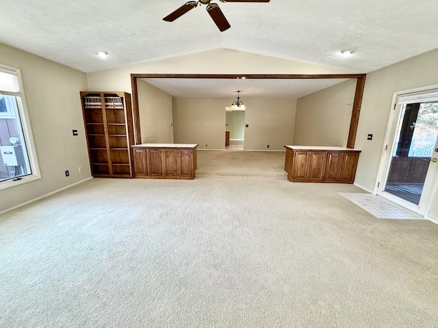 carpeted empty room with ceiling fan with notable chandelier, a textured ceiling, and vaulted ceiling