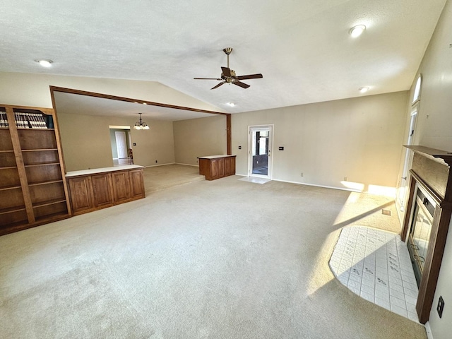 carpeted living room with a textured ceiling, ceiling fan with notable chandelier, and vaulted ceiling