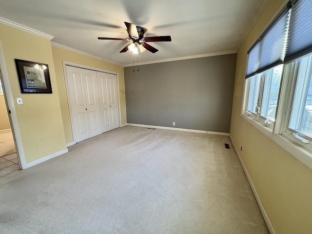 unfurnished bedroom with light carpet, a closet, ceiling fan, and ornamental molding