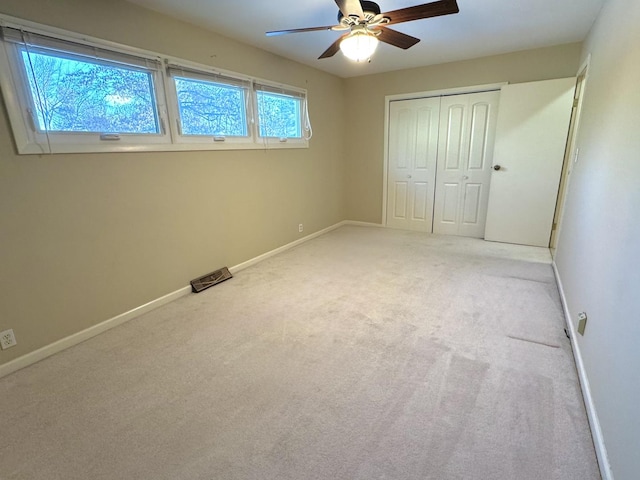 unfurnished bedroom featuring ceiling fan, light colored carpet, multiple windows, and a closet