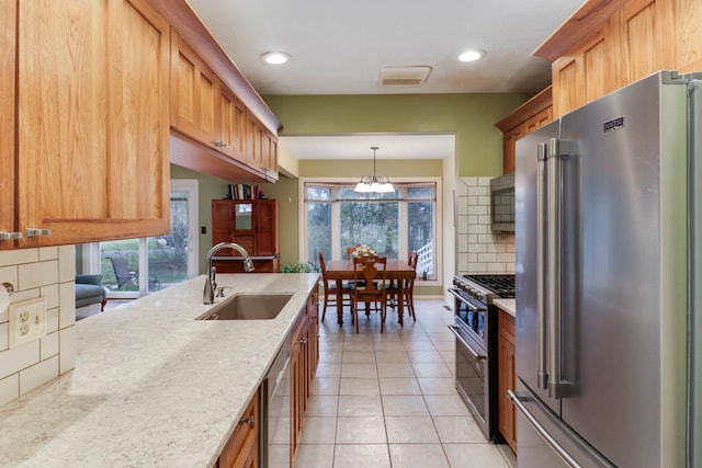 kitchen with high quality appliances, an inviting chandelier, sink, decorative backsplash, and light tile patterned floors