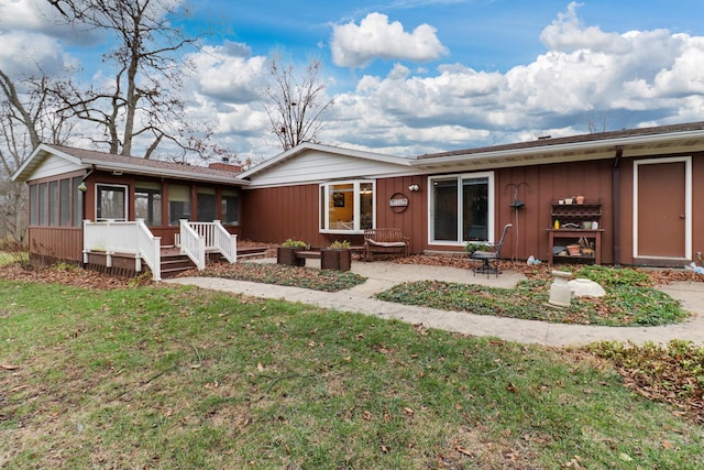 view of front of property with a sunroom, a front lawn, and a patio