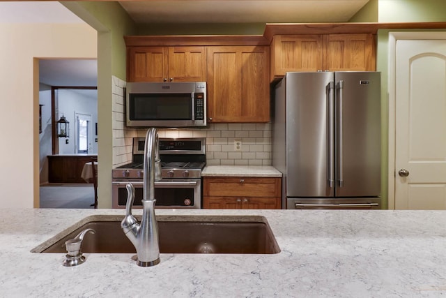 kitchen with light stone countertops, stainless steel appliances, and tasteful backsplash