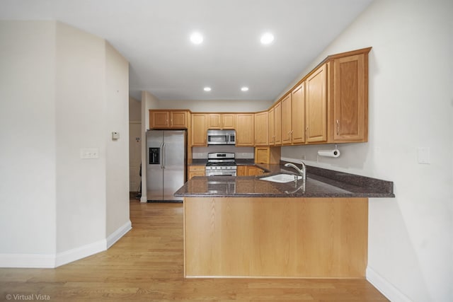 kitchen featuring light hardwood / wood-style floors, kitchen peninsula, sink, and appliances with stainless steel finishes