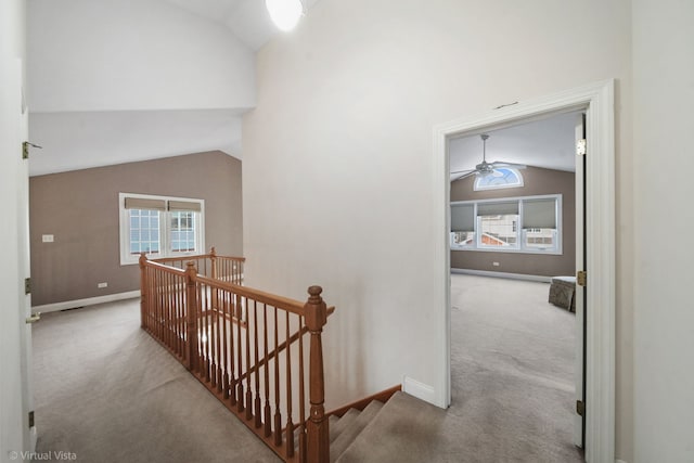 hallway with light colored carpet and vaulted ceiling