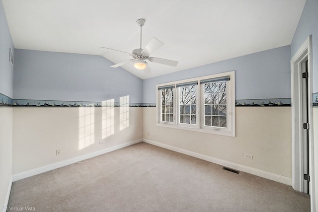 carpeted spare room with ceiling fan and vaulted ceiling