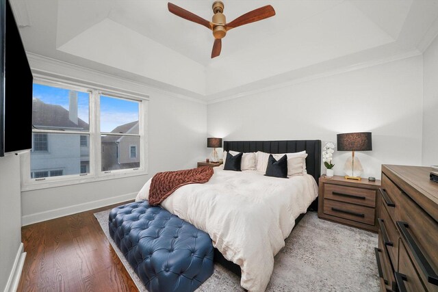 bedroom featuring hardwood / wood-style flooring, ceiling fan, crown molding, and a tray ceiling