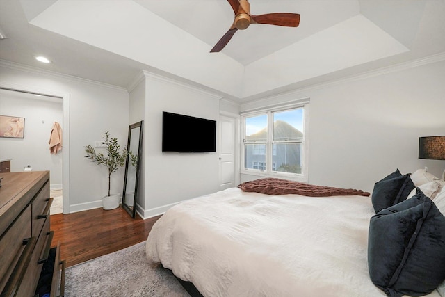 bedroom with a raised ceiling, ceiling fan, crown molding, and dark wood-type flooring