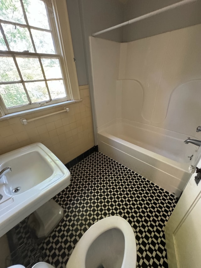 full bathroom featuring sink, tile patterned flooring, tile walls, toilet, and bathtub / shower combination