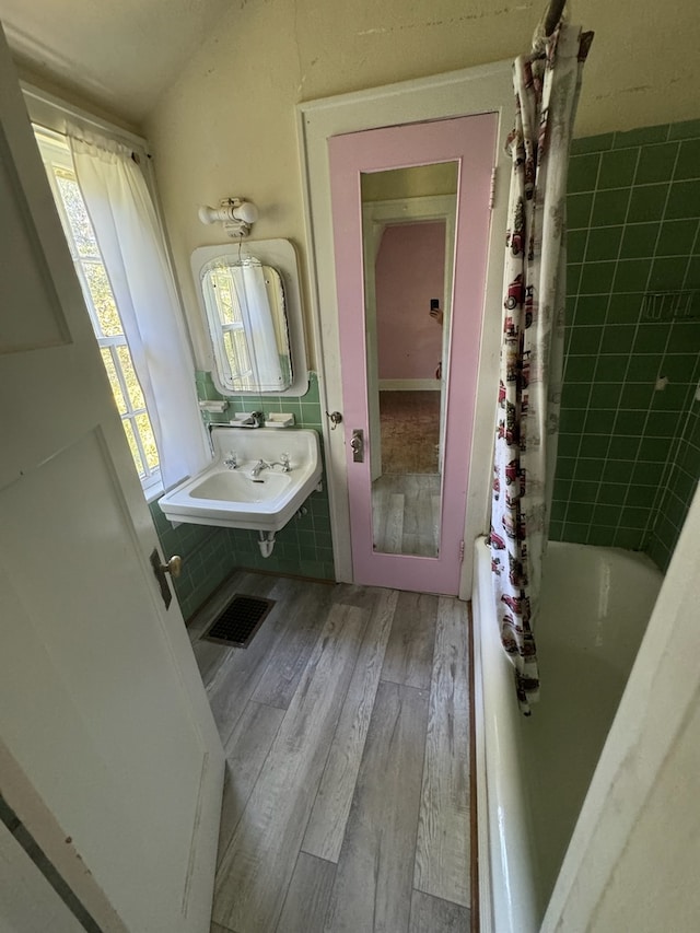 bathroom with hardwood / wood-style floors, shower / tub combo with curtain, and sink