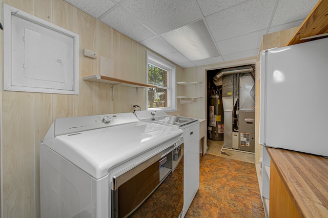 clothes washing area with washer and dryer, wood walls, gas water heater, and electric panel