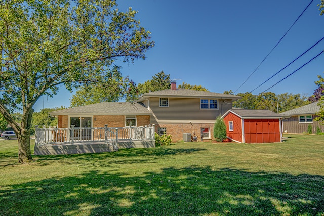 rear view of property featuring a lawn, a shed, and a deck