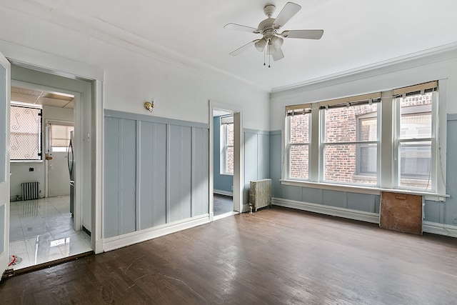 spare room with hardwood / wood-style flooring, ceiling fan, radiator heating unit, and crown molding