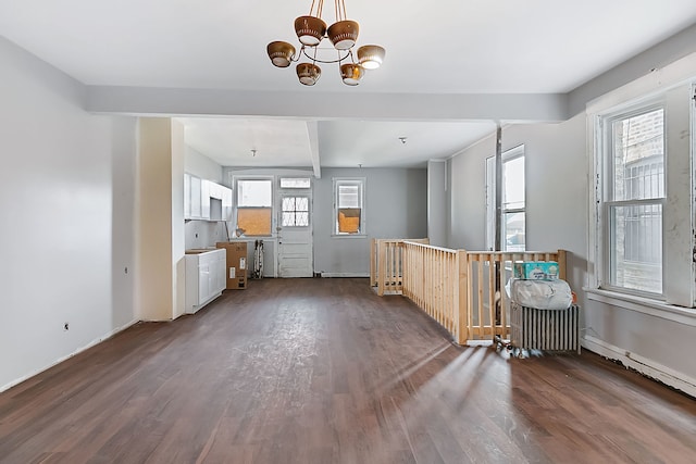 interior space with dark wood-type flooring, beamed ceiling, a healthy amount of sunlight, and an inviting chandelier