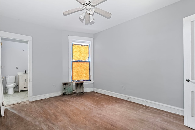 unfurnished bedroom featuring radiator, ensuite bath, ceiling fan, and wood-type flooring