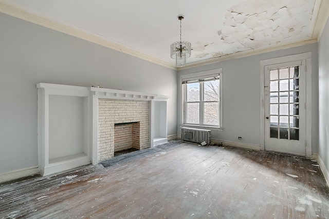 unfurnished living room featuring radiator, ornamental molding, a notable chandelier, a fireplace, and hardwood / wood-style flooring