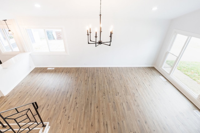 unfurnished dining area featuring a chandelier and hardwood / wood-style flooring