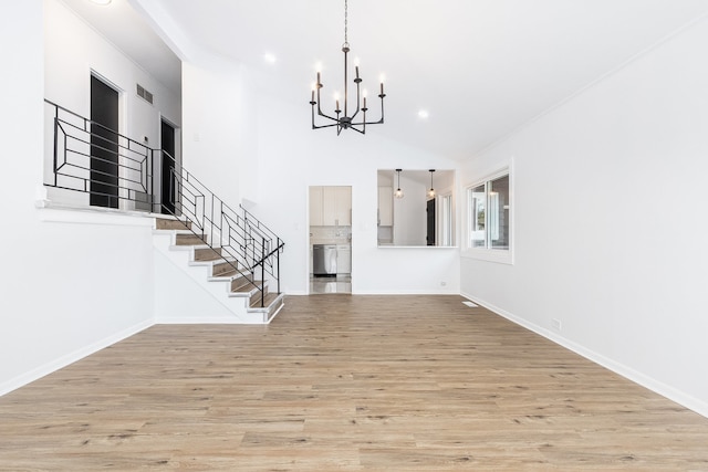 foyer entrance featuring a chandelier, light wood-type flooring, and high vaulted ceiling