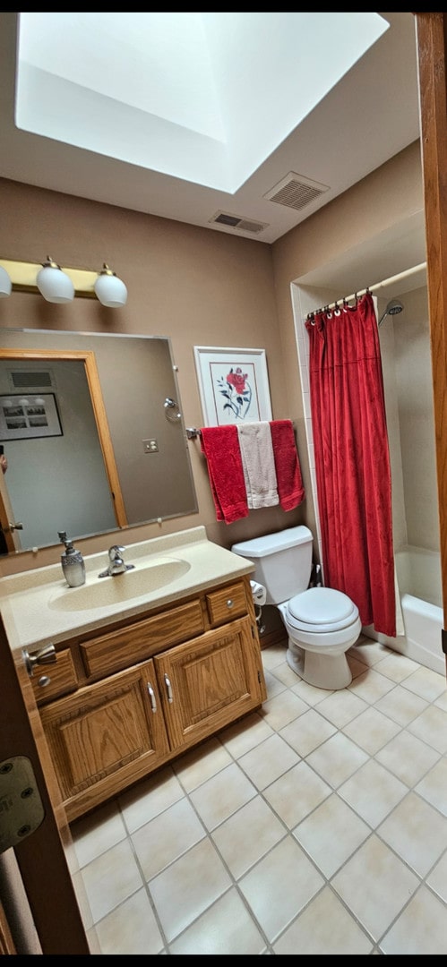 full bathroom with a skylight, tile patterned floors, toilet, shower / tub combo with curtain, and vanity