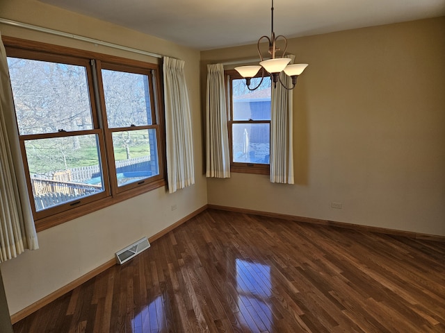 empty room featuring a chandelier and dark hardwood / wood-style flooring