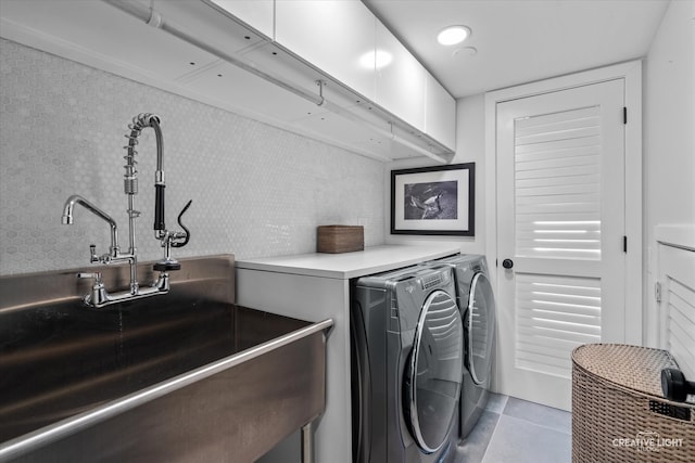 laundry area featuring light tile patterned floors, washer and clothes dryer, and sink