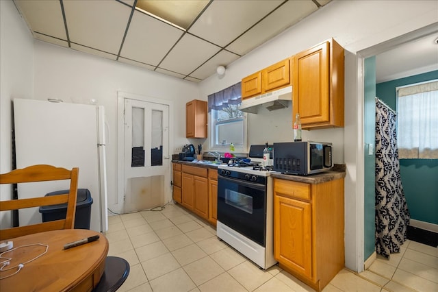 kitchen with a paneled ceiling, sink, light tile patterned floors, and white appliances