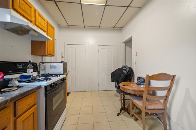 kitchen featuring a drop ceiling, light tile patterned floors, and white appliances