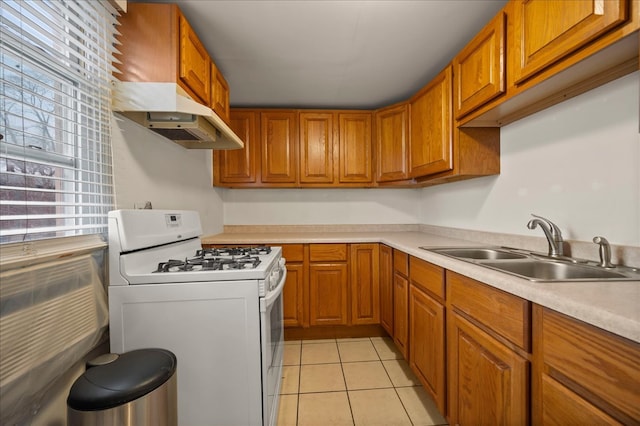 kitchen featuring white gas stove, light tile patterned floors, and sink