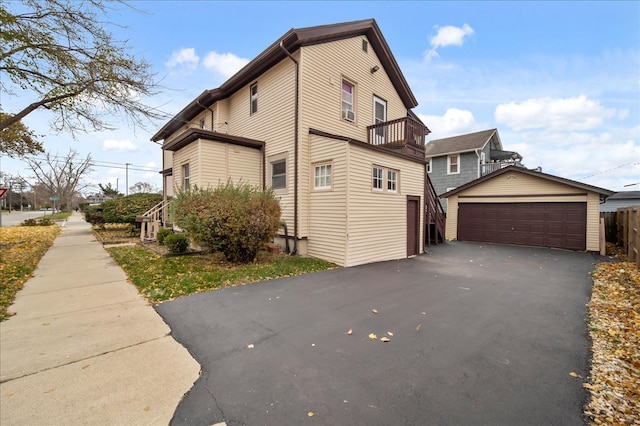 view of side of property featuring a garage, a balcony, and an outdoor structure