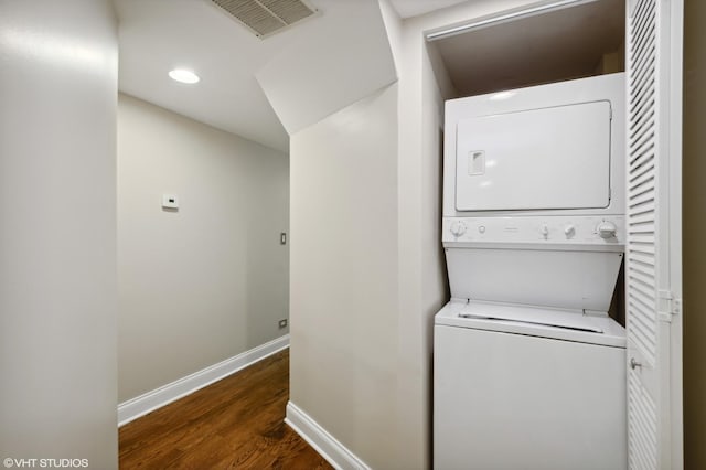 washroom with stacked washer and dryer and dark wood-type flooring