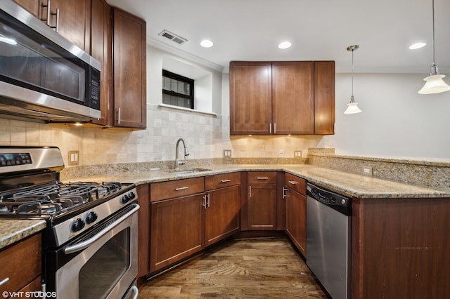 kitchen featuring dark wood-type flooring, sink, tasteful backsplash, decorative light fixtures, and stainless steel appliances