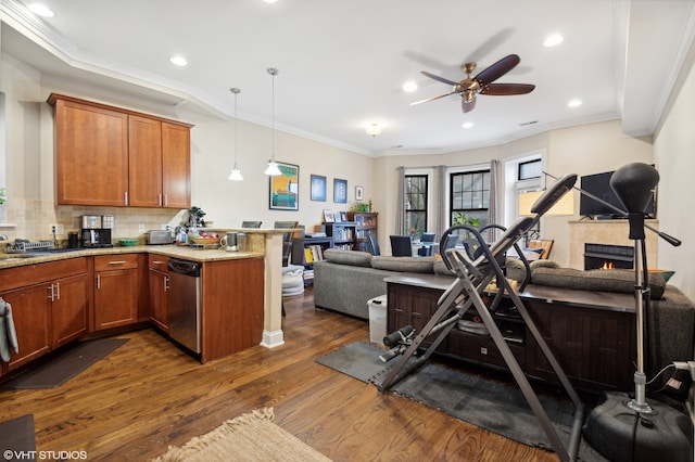 exercise area with dark hardwood / wood-style floors, ceiling fan, crown molding, and a tiled fireplace