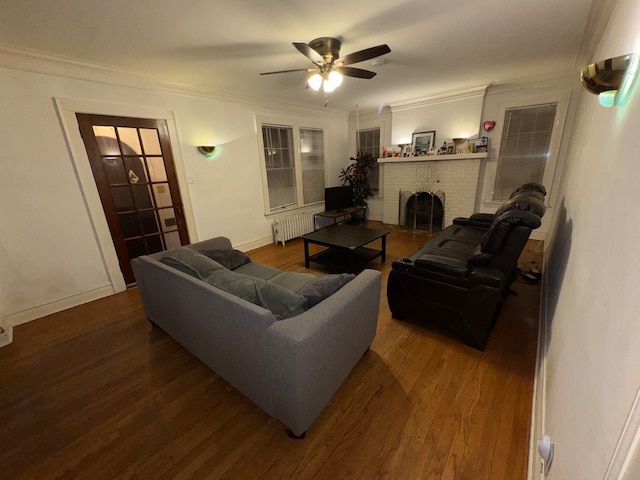 living room featuring hardwood / wood-style floors, radiator, a brick fireplace, ceiling fan, and ornamental molding