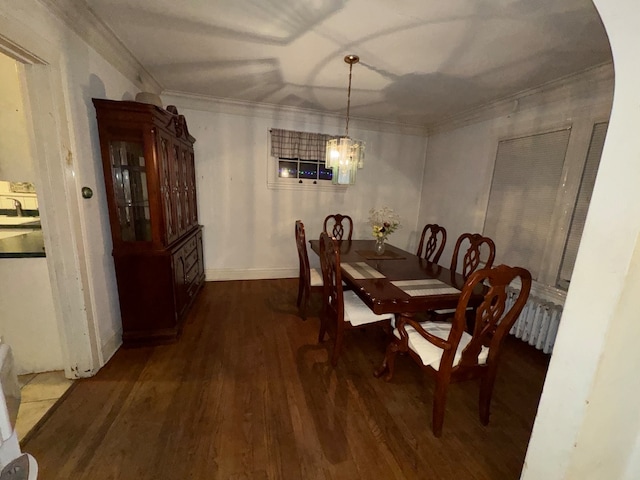 dining space with dark hardwood / wood-style flooring, ornamental molding, sink, and a chandelier