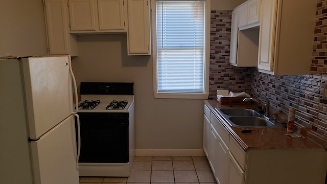 kitchen featuring white appliances, backsplash, sink, light tile patterned floors, and white cabinetry