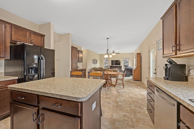 kitchen with black fridge, ceiling fan with notable chandelier, stainless steel dishwasher, and a kitchen island