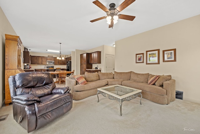 carpeted living room with ceiling fan with notable chandelier