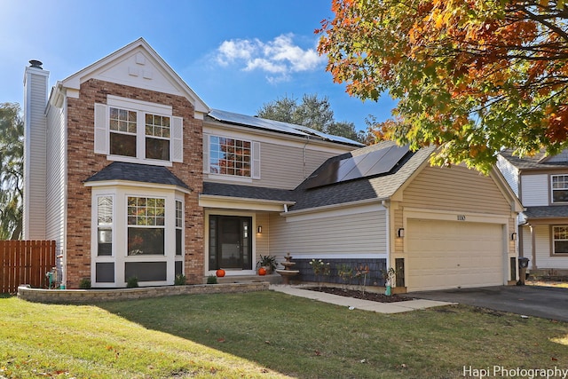 view of front of house featuring solar panels, a garage, and a front lawn