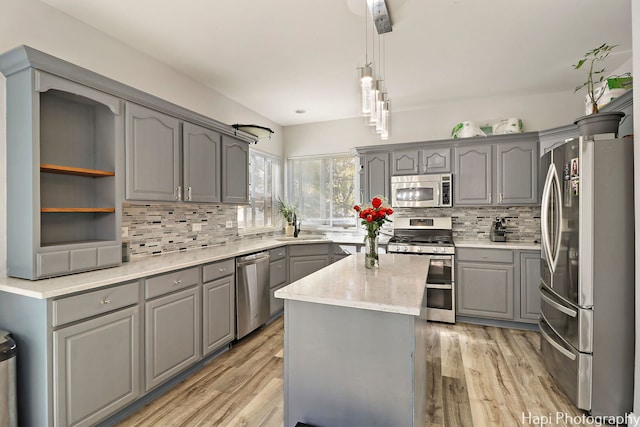 kitchen featuring appliances with stainless steel finishes, light hardwood / wood-style flooring, a kitchen island, and pendant lighting