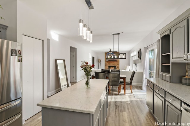 kitchen with appliances with stainless steel finishes, decorative light fixtures, a kitchen island, and gray cabinetry