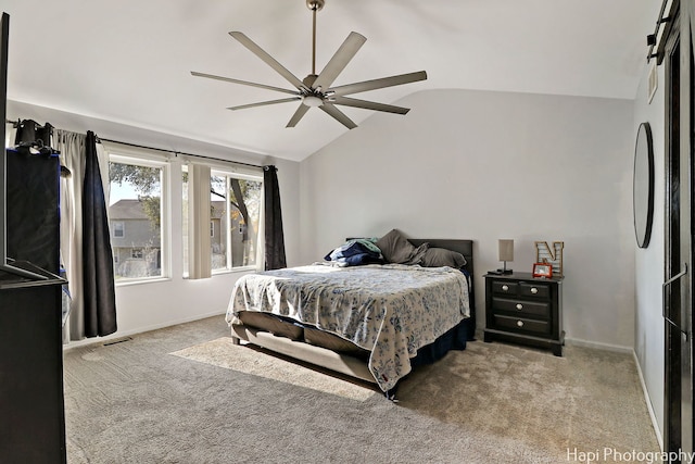 carpeted bedroom with ceiling fan, a barn door, and vaulted ceiling