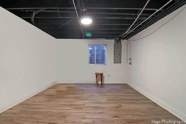 basement featuring electric panel and hardwood / wood-style flooring