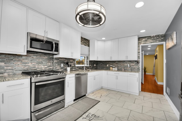 kitchen with light stone countertops, white cabinetry, and stainless steel appliances