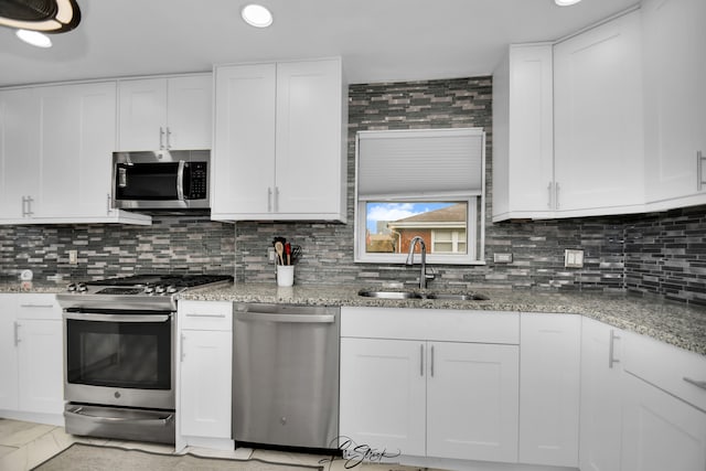 kitchen with backsplash, stainless steel appliances, white cabinetry, and sink