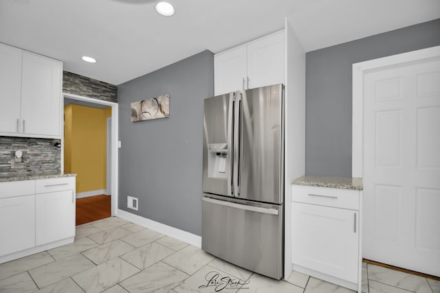 kitchen featuring white cabinetry, light stone countertops, stainless steel fridge with ice dispenser, and backsplash